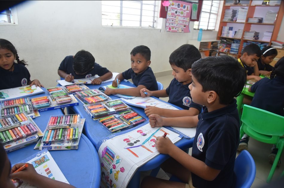 Young Royal Concorde students working with crayons and workbooks in class
