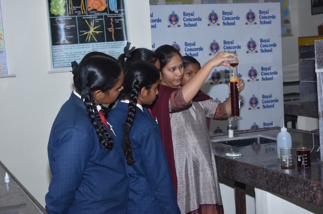 Students watching a teacher carry out an experiment in the Royal Concorde science laboratory
