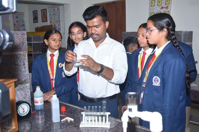 A teacher demonstrating an experiment to senior students at a laboratory bench