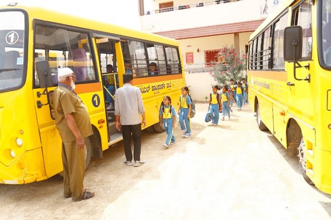 Students boarding a Royal Concorde school bus under staff supervision