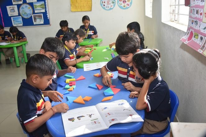 Students working with coloured shape tiles and workbooks in the maths lab