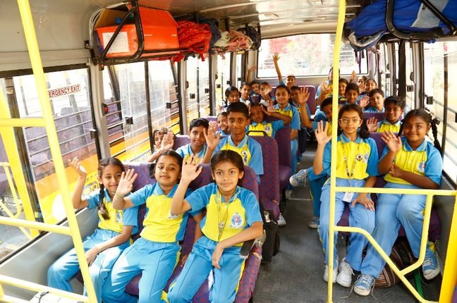 Students waving from their seats inside a Royal Concorde school bus